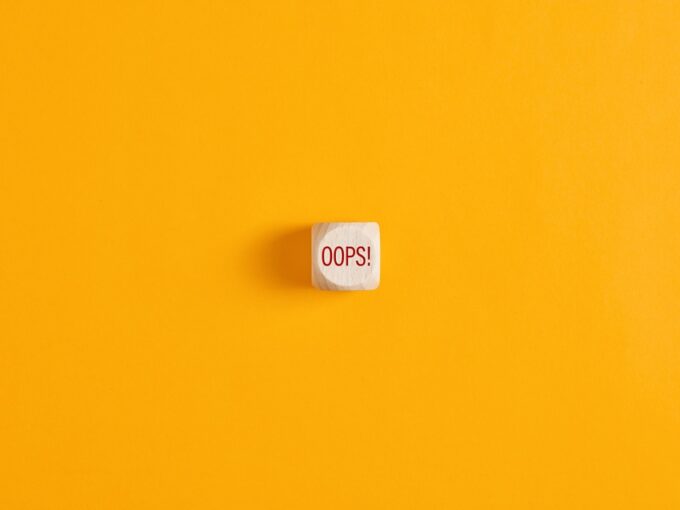 "Oops" scritto su un cubo di legno su sfondo giallo